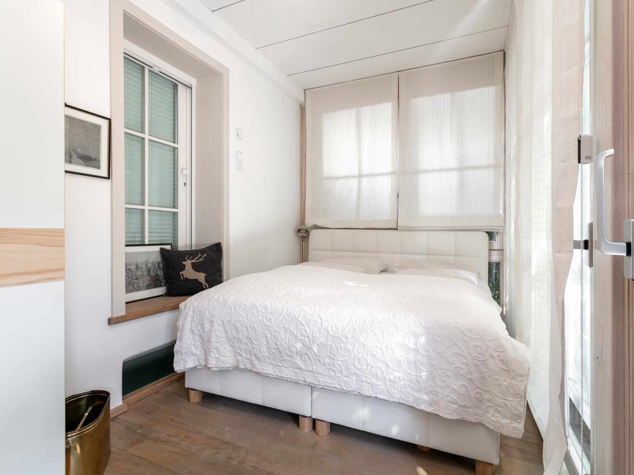 Un dormitorio con una cama, una ventana con persianas, un marco de cuadro y un cubo de basura.