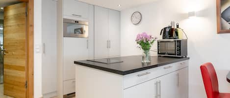 Een moderne keuken met een inbouwoven, een magnetron en een koffiezetapparaat op het aanrecht.