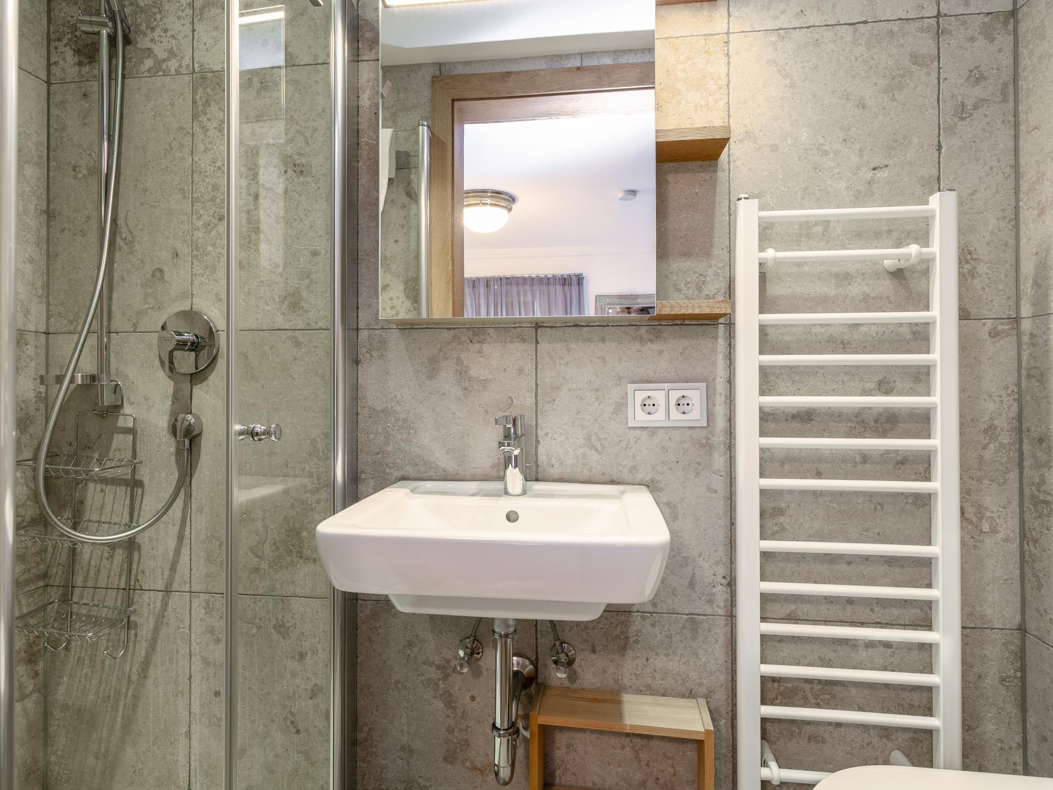 Une salle de bain avec une douche à parois de verre, un lavabo blanc, un miroir et un porte-serviettes blanc.