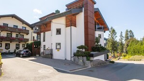 Ein modernes, zweistöckiges Gebäude mit flachem Dach, großen Fenstern und einem Balkon mit Holzgeländern.
