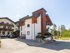 Ein modernes, zweistöckiges Gebäude mit flachem Dach, großen Fenstern und einem Balkon mit Holzgeländern.
