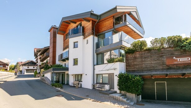 Ein modernes, mehrstöckiges Gebäude mit flachem Dach, großen Fenstern und einer Kombination aus Holz und Metall.