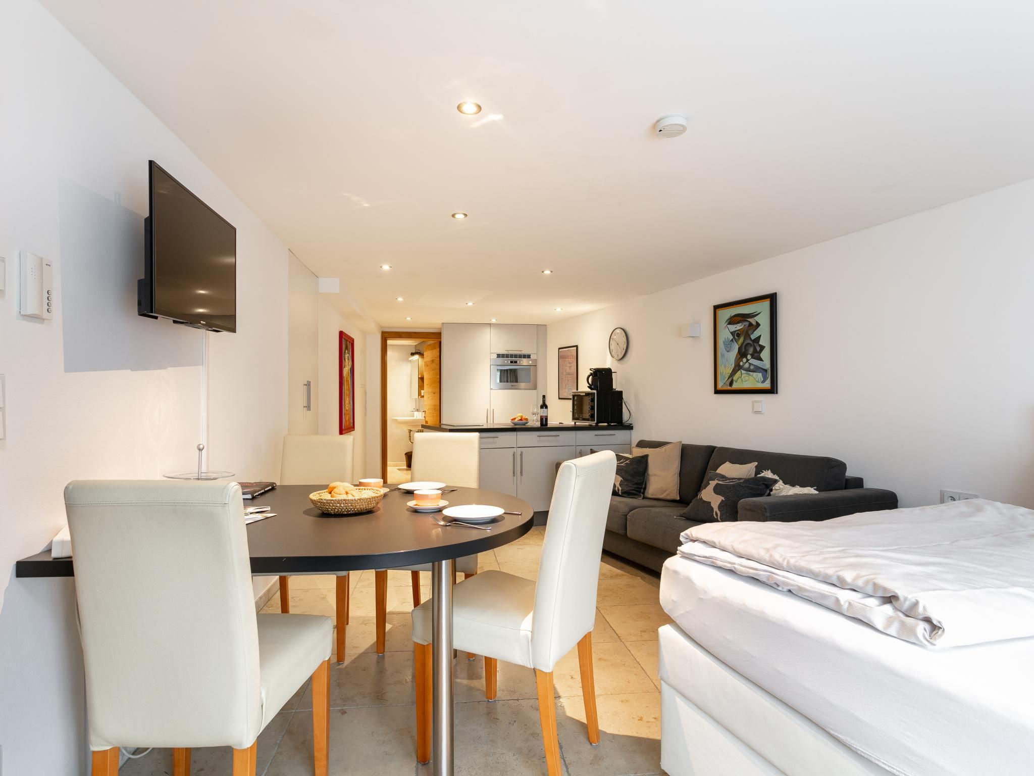 Una habitación moderna y luminosa con mesa de comedor, sillas, sofá y cama.