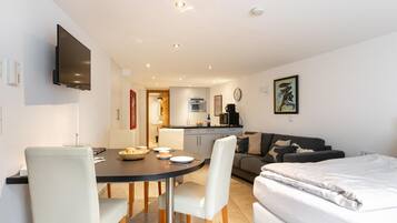 Una habitación moderna y luminosa con mesa de comedor, sillas, sofá y cama.
