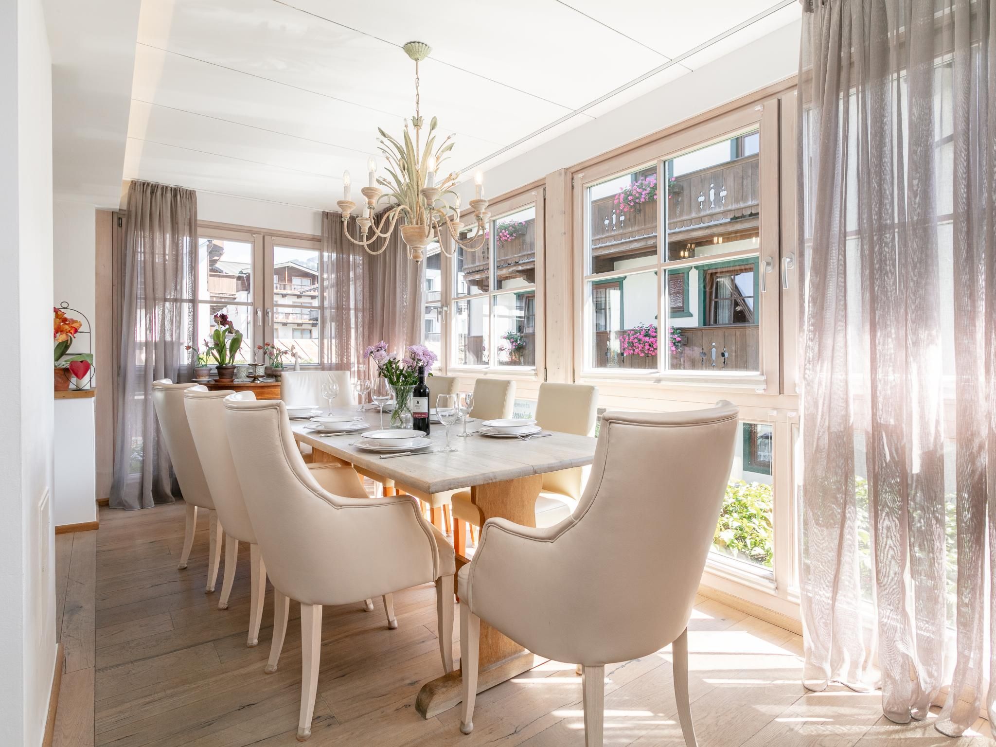 Une salle à manger avec une table en bois dressée pour quatre personnes, entourée de six chaises.