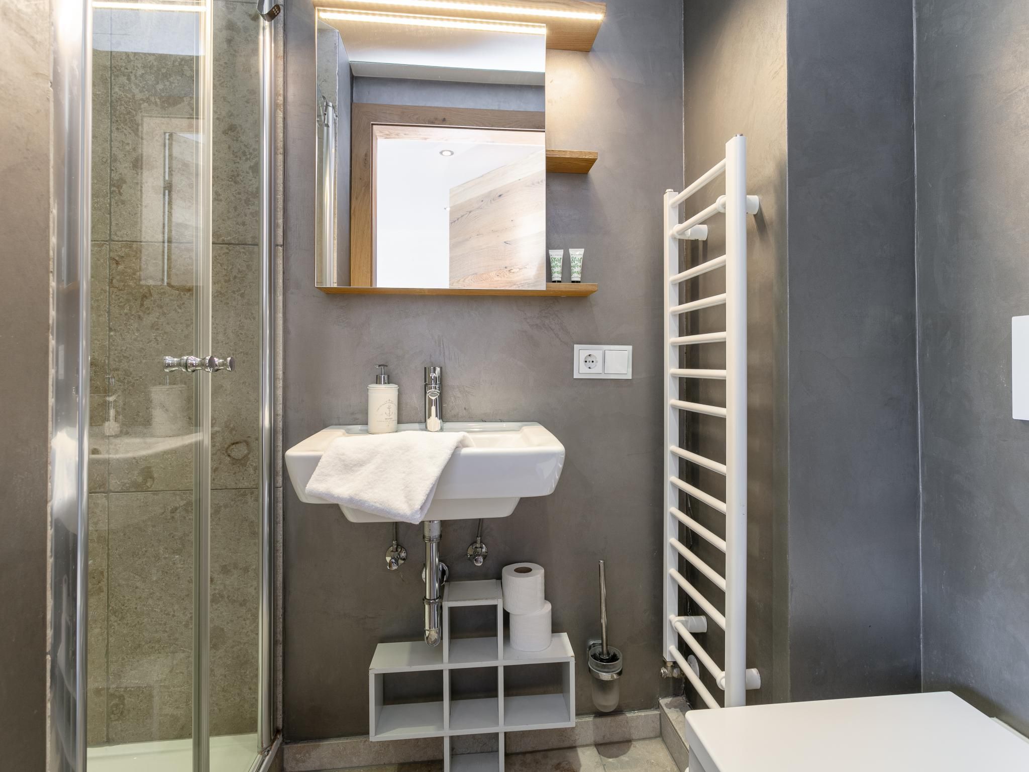 Une salle de bain moderne avec une douche à parois de verre, un lavabo blanc avec une serviette et un porte-serviettes.