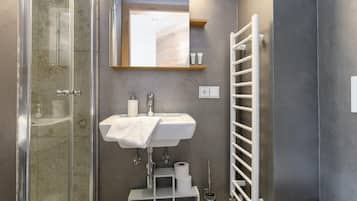 Une salle de bain moderne avec une douche à parois de verre, un lavabo blanc avec une serviette et un porte-serviettes.