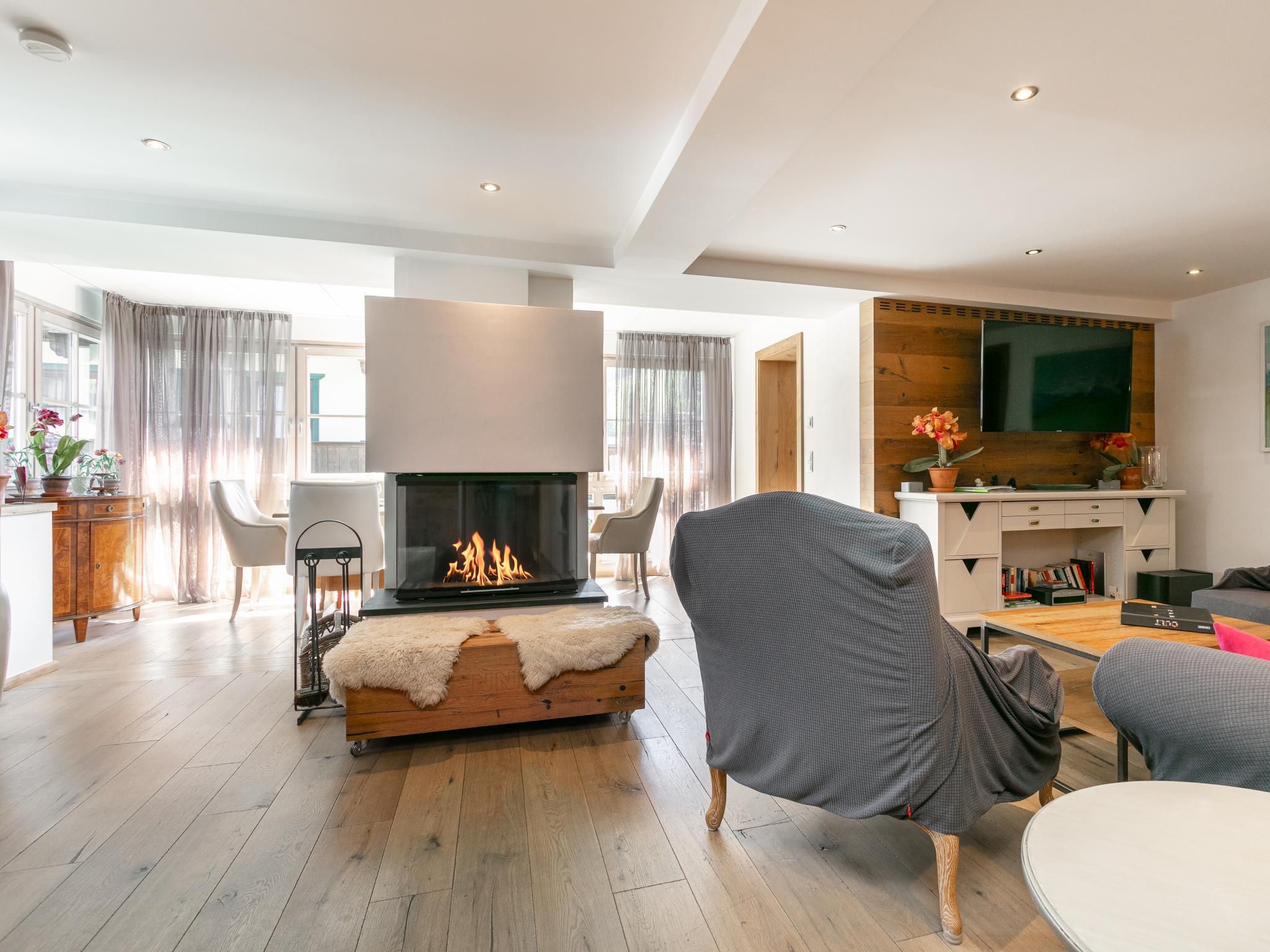 Ein modernes Wohnzimmer mit Kamin, Fernseher und Essbereich.