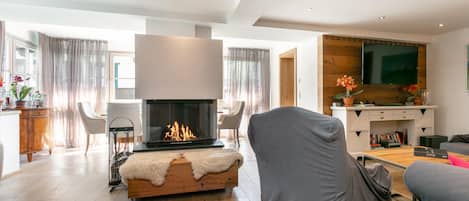 A modern living room with a fireplace, a television, and a dining area.