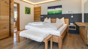 Ein modernes Schlafzimmer mit einem Holzbett, Nachttischen, einer Bank und Kunstwerken an den Wänden.