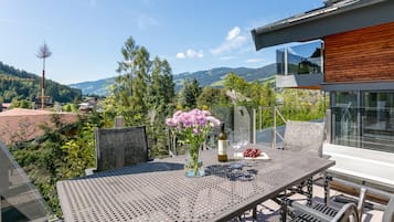 Un espace de restauration en plein air avec une table, des chaises, un vase de fleurs et une bouteille de vin.