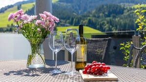 Ein Tisch mit einer Weinflasche, zwei Gläsern, einer Blumenvase und einer Traube.