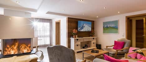 A modern living room with a fireplace, comfortable seating, and a television.