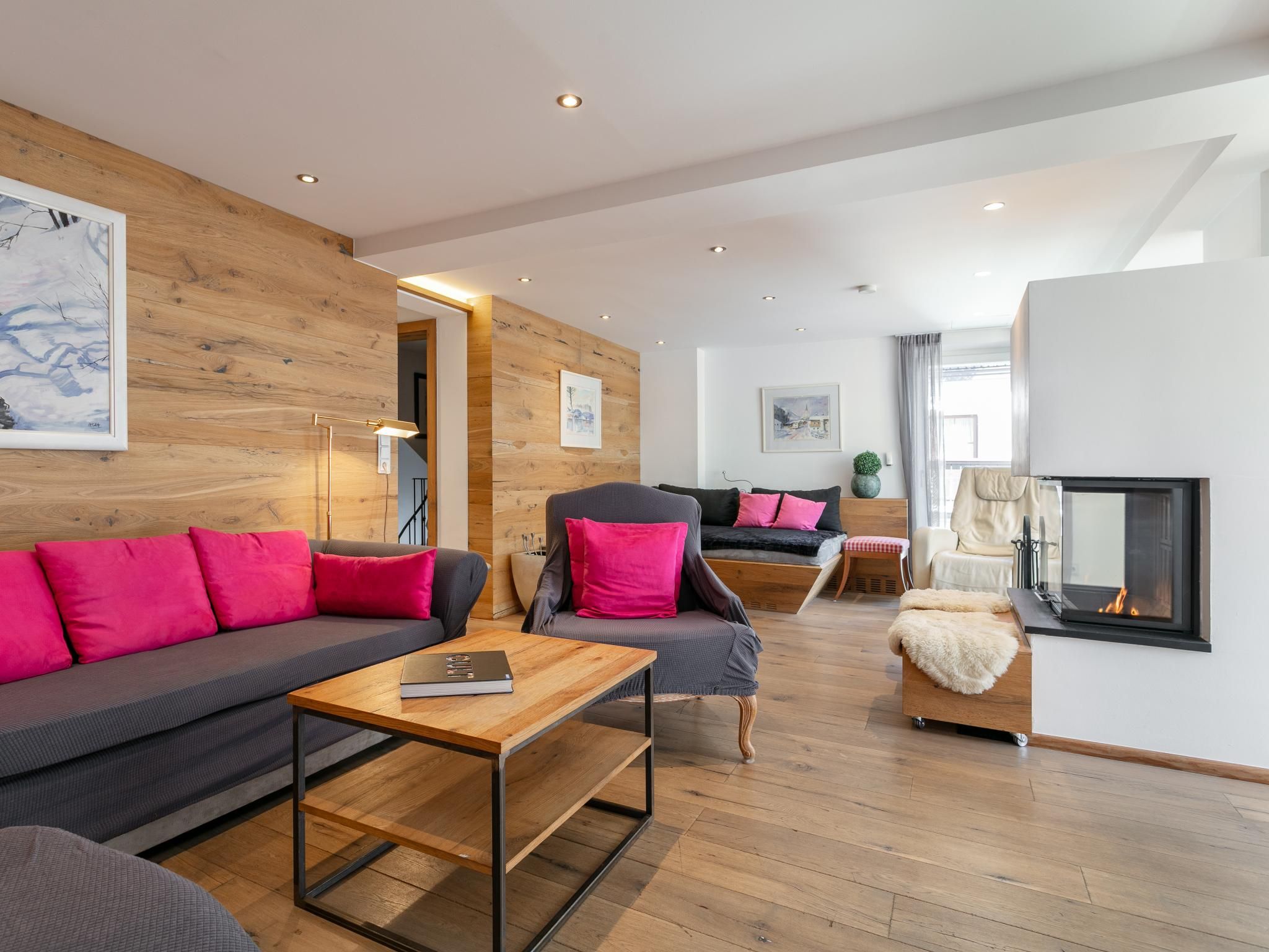 Ein modernes Wohnzimmer mit Holzboden, einer Couch, einem Sessel und einem Kamin.