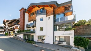 Ein modernes, mehrstöckiges Wohngebäude mit Balkonen, großen Fenstern und einer Holzfassade.