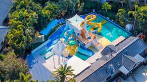 Un parc aquatique avec des toboggans et des piscines, entouré de palmiers.