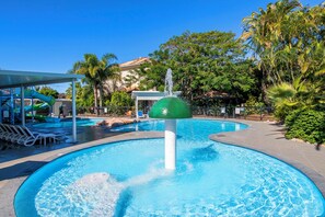 A swimming pool with a water fountain, lounge chairs, and a covered area with a slide. - Turtles -Water Park Resort - Mermaid Beach (Mermaid Beach)