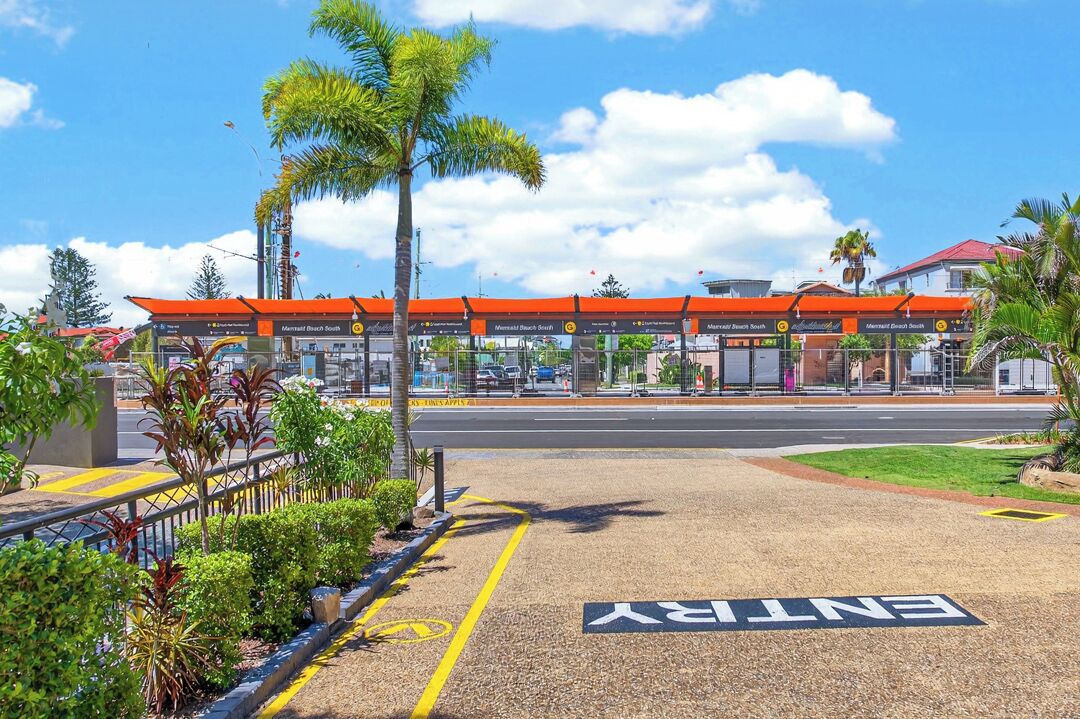 Eine Tankstelle mit mehreren Zapfsäulen, blauem Himmel und einer Palmenbaum im Vordergrund.