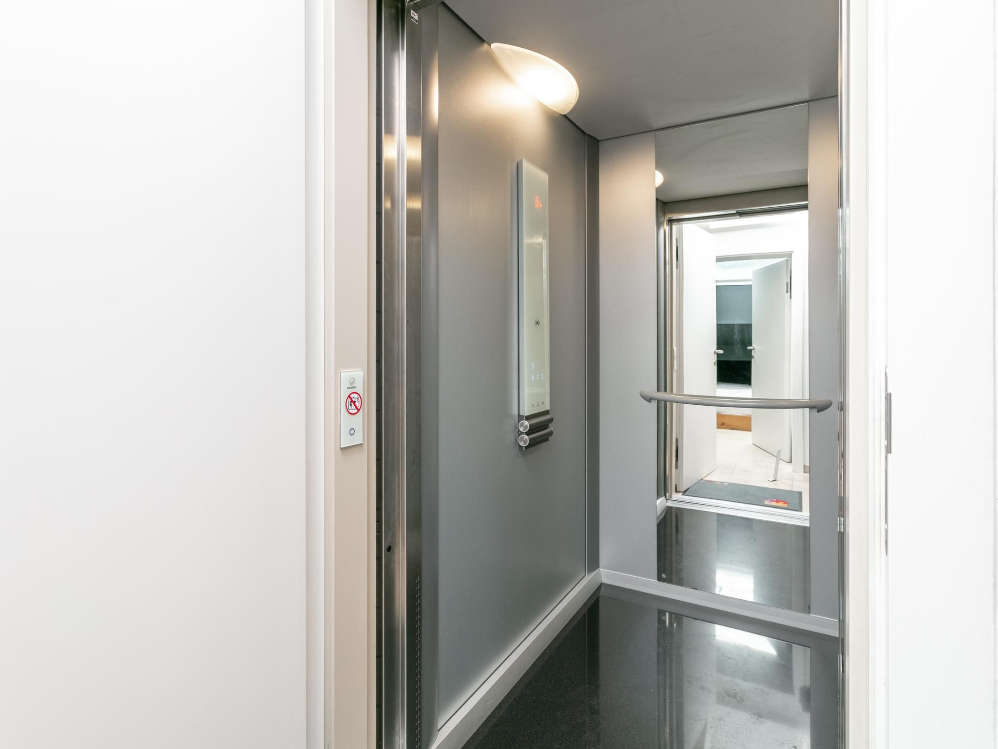 Een moderne lift met een digitaal scherm en een leuning.