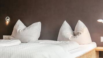 Une chambre d’hôtel comprenant un lit, des oreillers, une table de chevet et un luminaire fixé au mur.