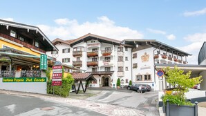 Un hotel de estilo alpino tradicional, con balcones adornados con macetas de flores y un escudo destacado en la fachada.