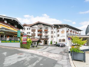 Ein Hotel im traditionellen alpinen Baustil, mit Balkonen, die mit Blumenkästen geschmückt sind, und einem markanten Wappen an der Fassade.