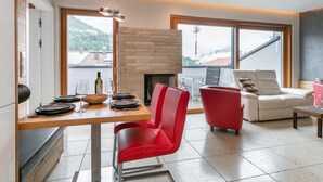Una sala de estar moderna con chimenea, comedor y ventanas amplias que ofrecen vistas al exterior.