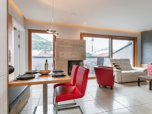 Ein modernes Wohnzimmer mit Kamin, Essbereich und großen Fenstern mit Blick ins Freie.