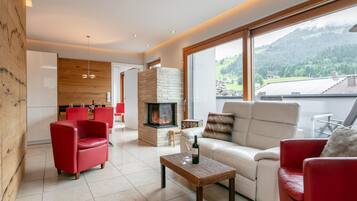 Una sala de estar moderna con chimenea, sillas rojas, un sofá y vistas al exterior.