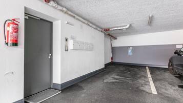 Een parkeergarage met een brandblusser aan de muur, een deur en een ventilatiesysteem.