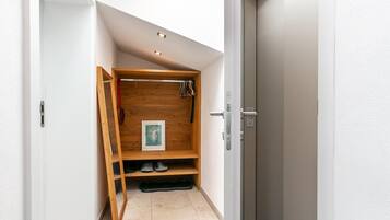Un pasillo con un mueble de almacenamiento de madera, una puerta y suelo de baldosas.