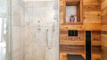 Une salle de bain moderne avec une douche à parois de verre, un lambris mural en bois, un petit lavabo avec un receveur violet et une poubelle noire.