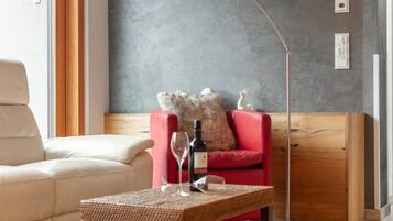 A modern living room with a beige sofa, a red armchair, a wooden coffee table, and a floor lamp.