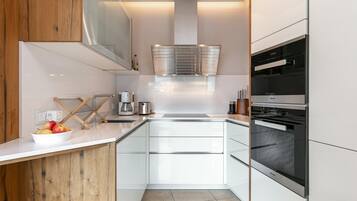 Een moderne keuken met witte kasten, roestvrijstalen apparatuur en een wand bekleed met hout.