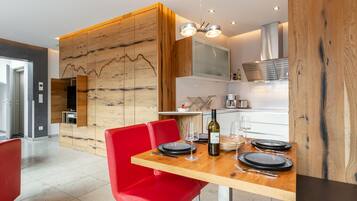 A modern kitchen with wooden accents, a dining table set with plates, glasses, and a bottle of wine.
