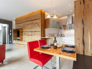 A modern kitchen with wooden accents, a dining table set with plates, glasses, and a bottle of wine.