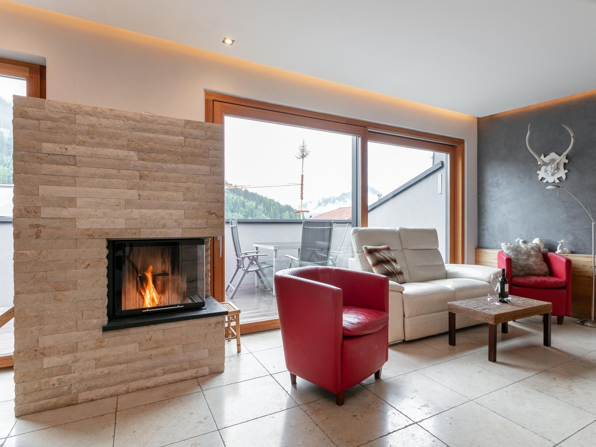Una sala de estar moderna con chimenea, un sofá de cuero rojo, un sofá blanco y una zona de comedor con una mesa y sillas.