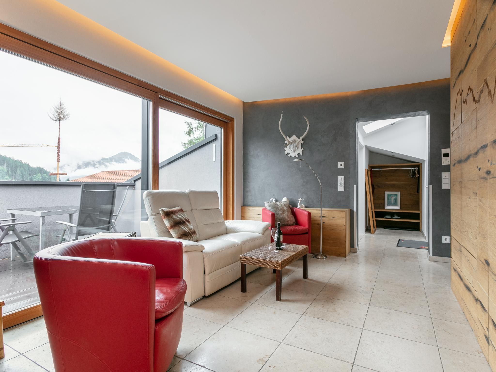 Un salon moderne avec un fauteuil rouge, un canapé blanc et une table en verre.