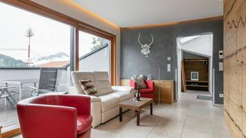 Un salon moderne avec un fauteuil rouge, un canapé blanc et une table en verre.
