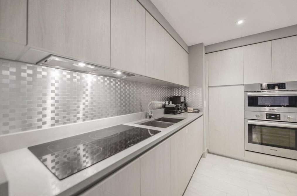 Una cocina moderna con cubierta negra, electrodomésticos de acero inoxidable y salpicadero de azulejos.