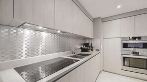 A modern kitchen with a black countertop, stainless steel appliances, and a tiled backsplash. - High Floor 2BR-2BA | Resort & Parking Fee Included (Hollywood)
