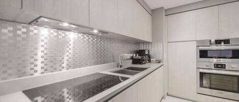 A modern kitchen with a black countertop, stainless steel appliances, and a tiled backsplash.