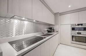 A modern kitchen with a black countertop, stainless steel appliances, and a tiled backsplash. - High Floor 2BR-2BA | Resort & Parking Fee Included (Hollywood)