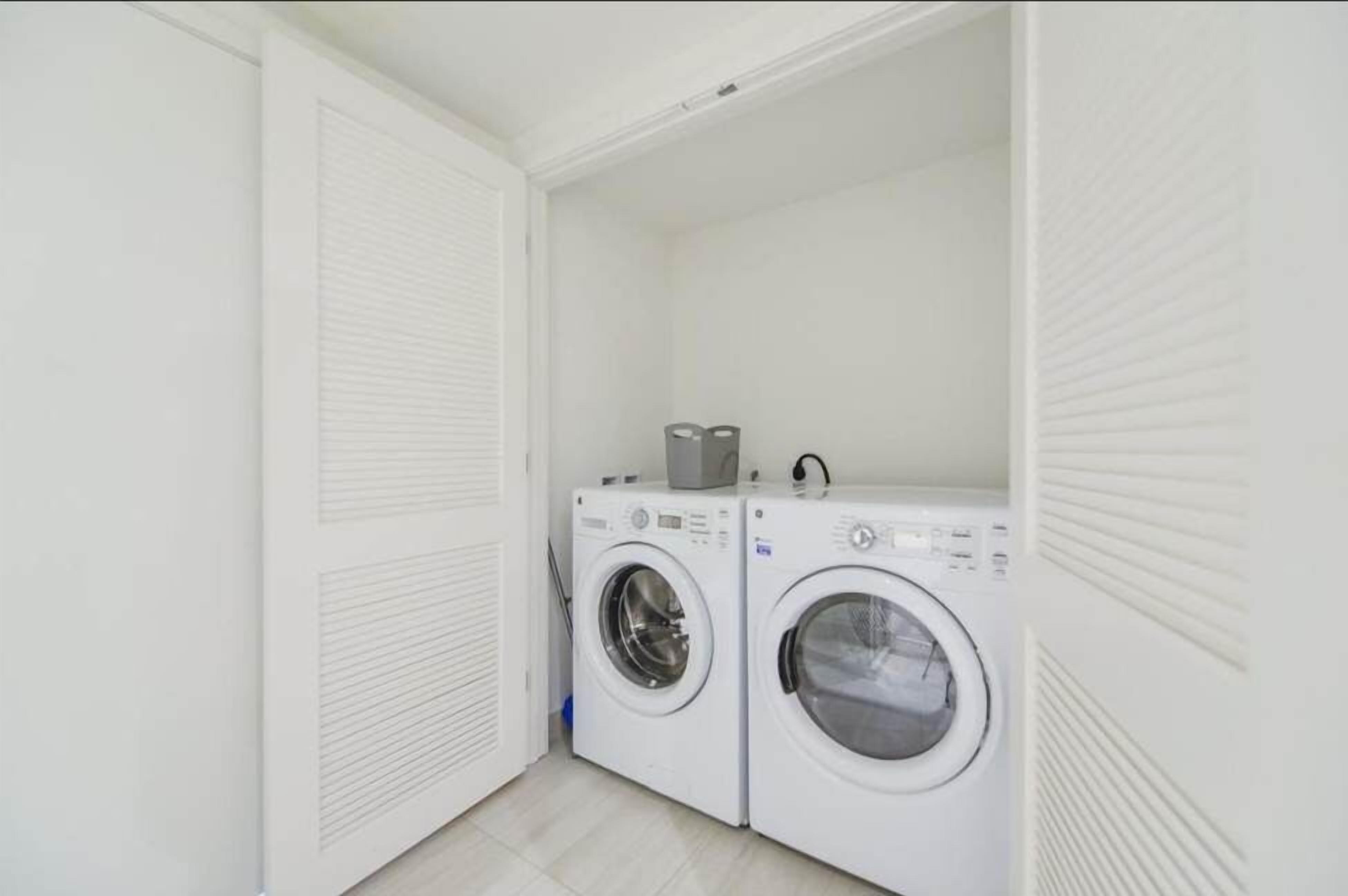 A laundry room with two front-loading washing machines and a dryer.