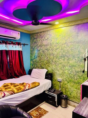 Un dormitorio con cama, cortinas, una pared con textura, ventilador de techo y mesita de noche con lámpara.