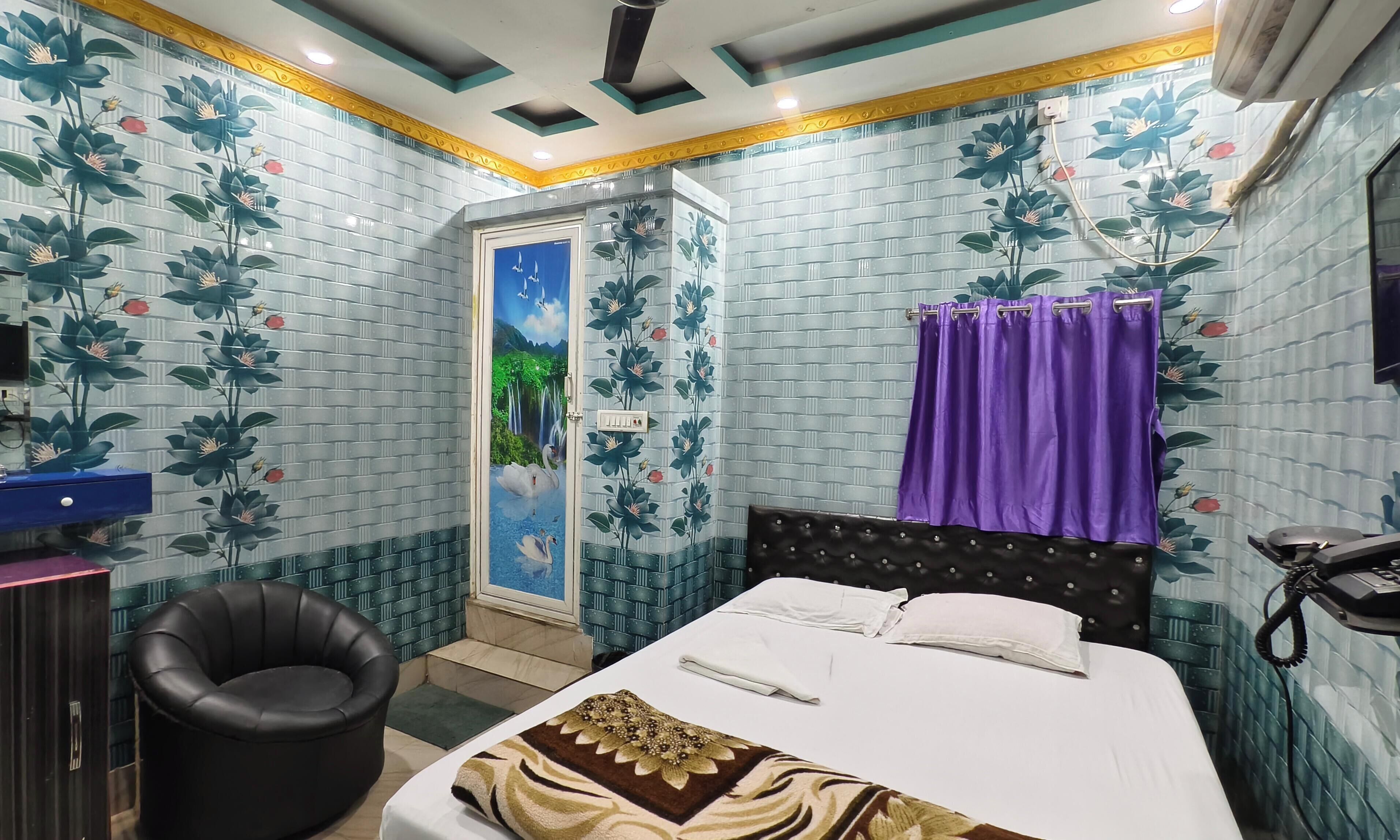 A bedroom with a bed, a chair, a wardrobe, and a bathroom with a shower curtain.
