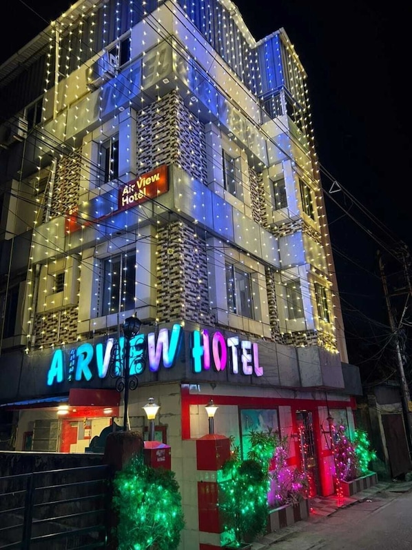 Un hôtel à plusieurs étages, reconnaissable à son grand panneau néon sur lequel on peut lire « Air View Hotel ».