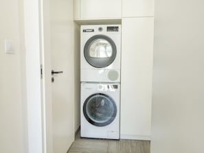 A compact laundry room with a front-loading washer and dryer stacked vertically. - Nový Smíchov by Interhome (Smichov Kosire Jinonice)