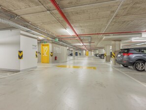 A multi-level underground parking garage with concrete pillars, yellow directional arrows, and a few parked cars. - Nový Smíchov by Interhome (Smichov Kosire Jinonice)