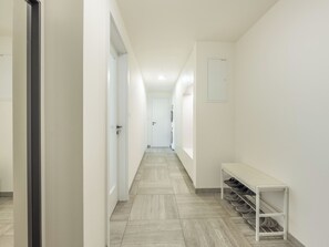 A corridor with a bench and shoe rack, leading to a door with a laundry machine. - Nový Smíchov by Interhome (Smichov Kosire Jinonice)